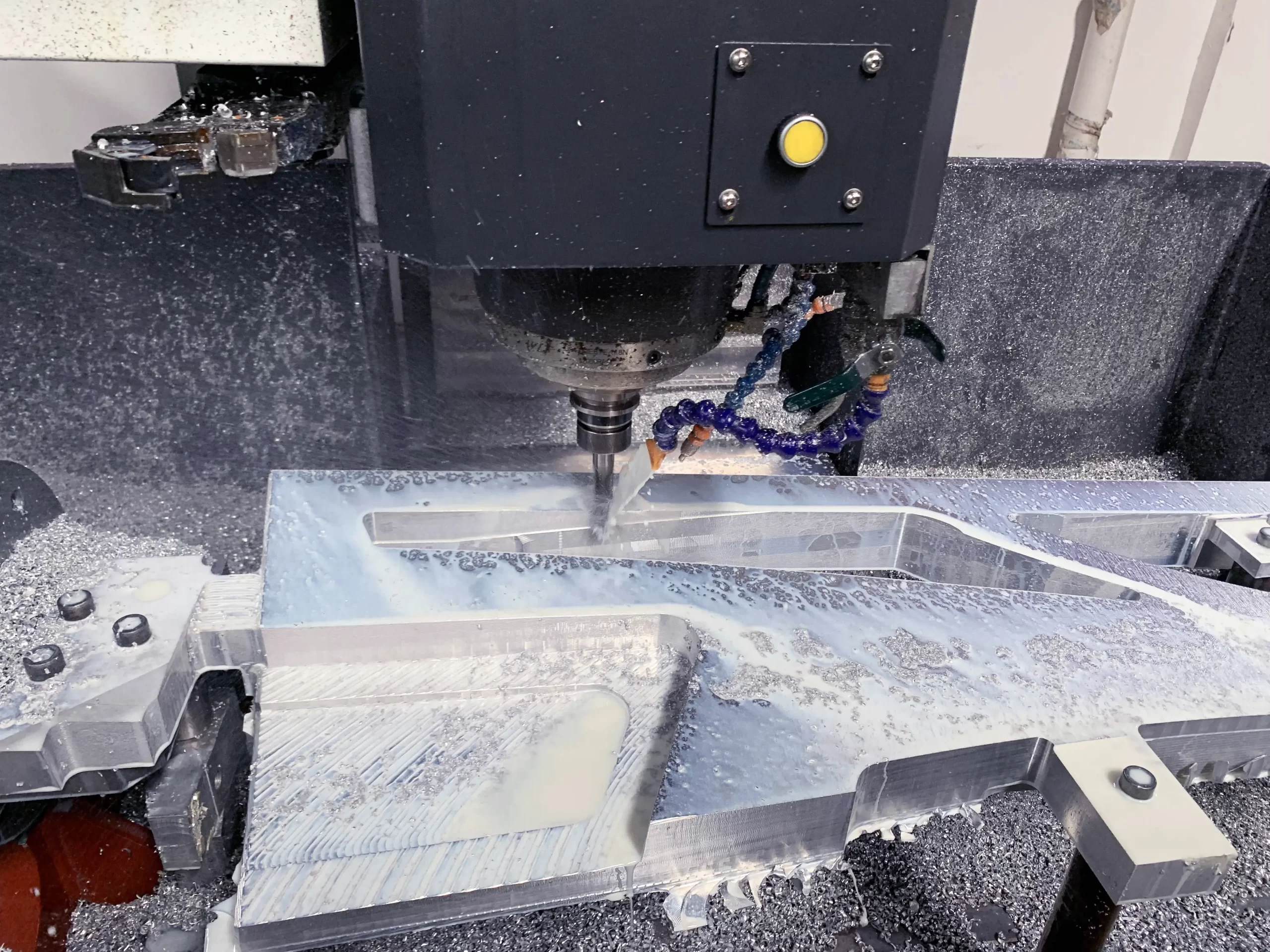 Close-up of a CNC machine tool cutting an aluminum part, with coolant fluid enabling precision machining.