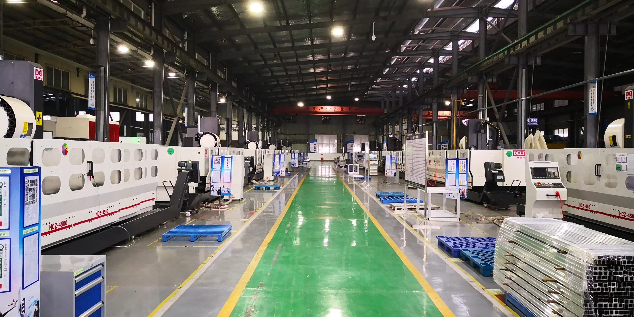 A wide-angle view of a modern CNC machining factory, featuring rows of industrial machining centers. The facility has a clean, organized layout with marked pathways, highlighting high-volume production capabilities for industries like automotive and aerospace.
