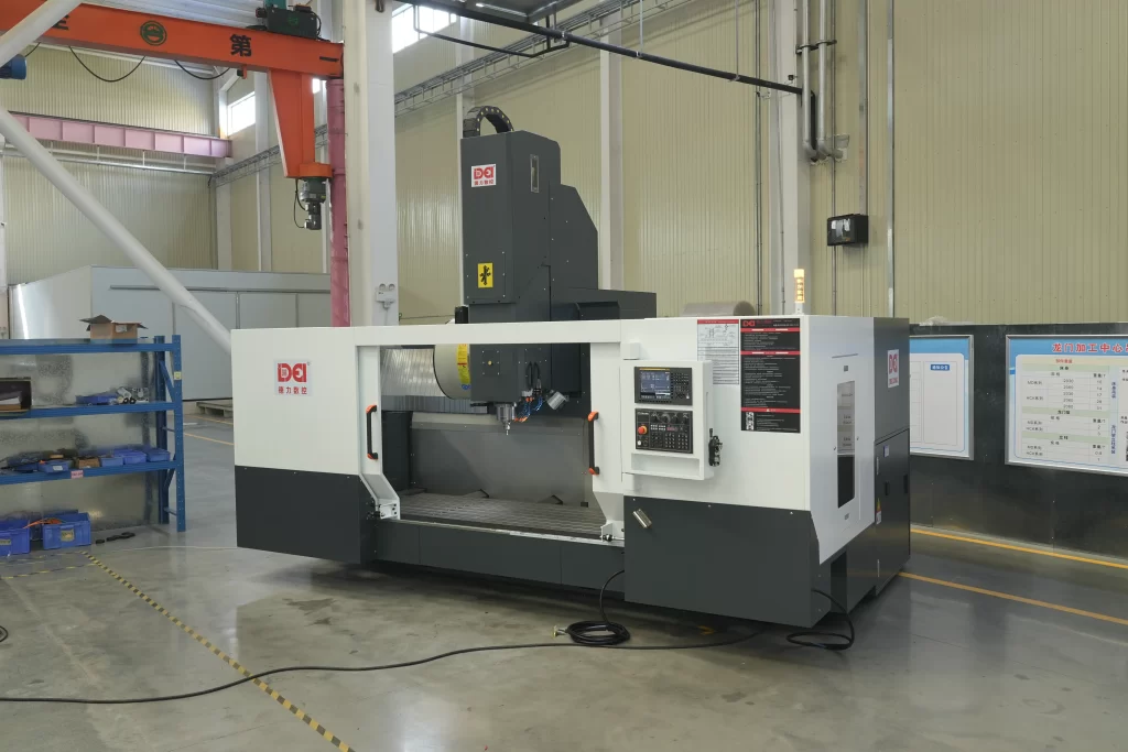 A large vertical machining center in a factory. It has a white - gray body, a red warning light, and blue racks/equipment in the background.
