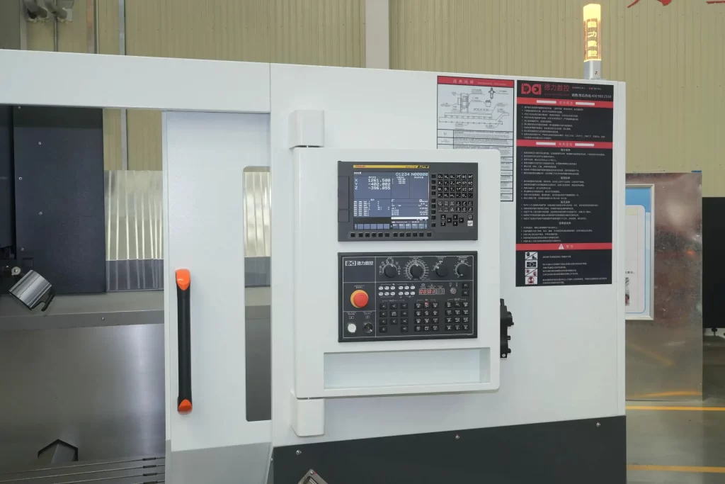 Close - up of a vertical machining center’s control panel, featuring a display, buttons, and labels. The machine body is white with black details.