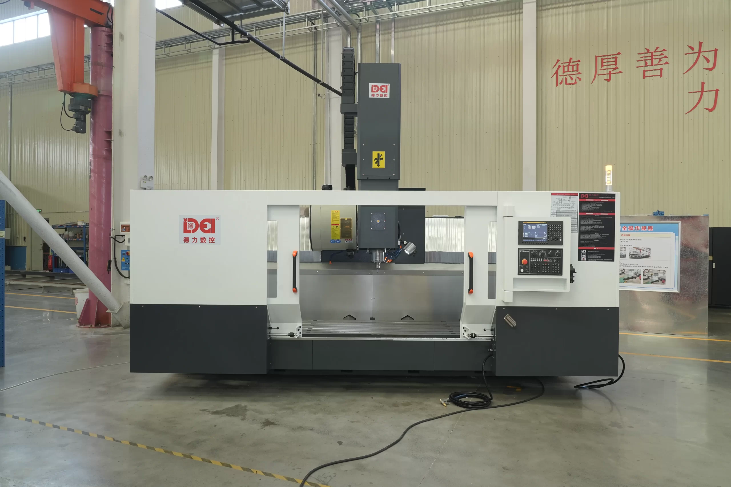 Full view of a CNC vertical machining center in an industrial workshop, showing the overall structure, control panel, and workspace.