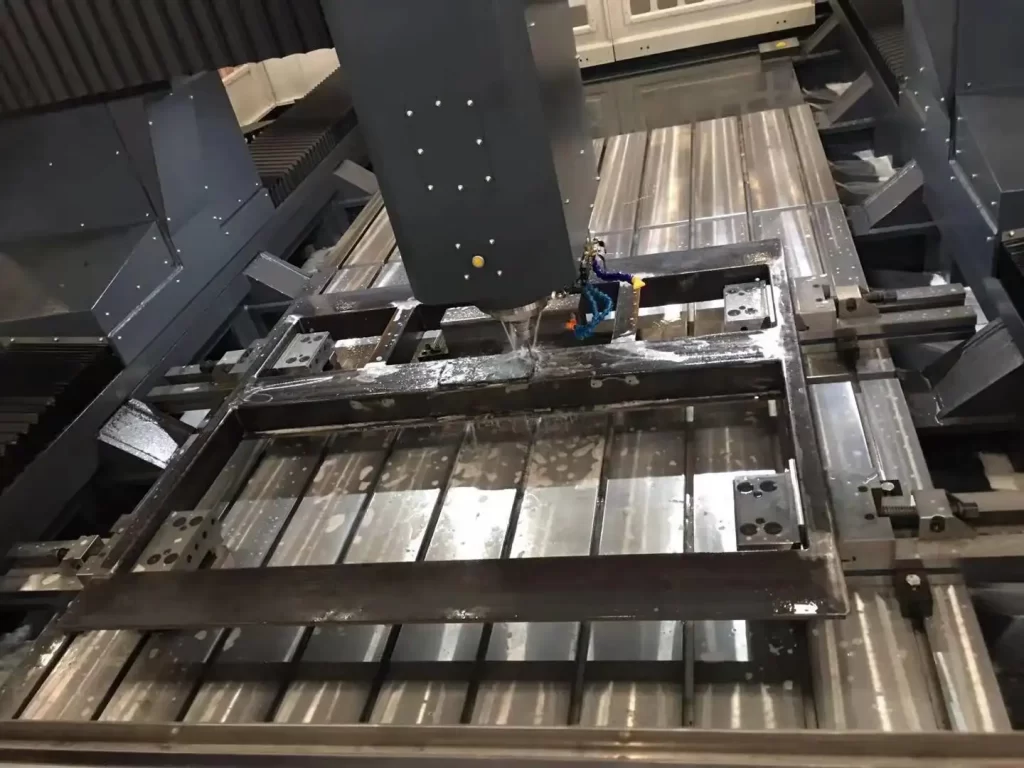 A large CNC machining center is processing a metal frame. The equipment has a precise structure, and metal parts are positioned orderly on the workbench, demonstrating the efficiency and precision of industrial processing.
