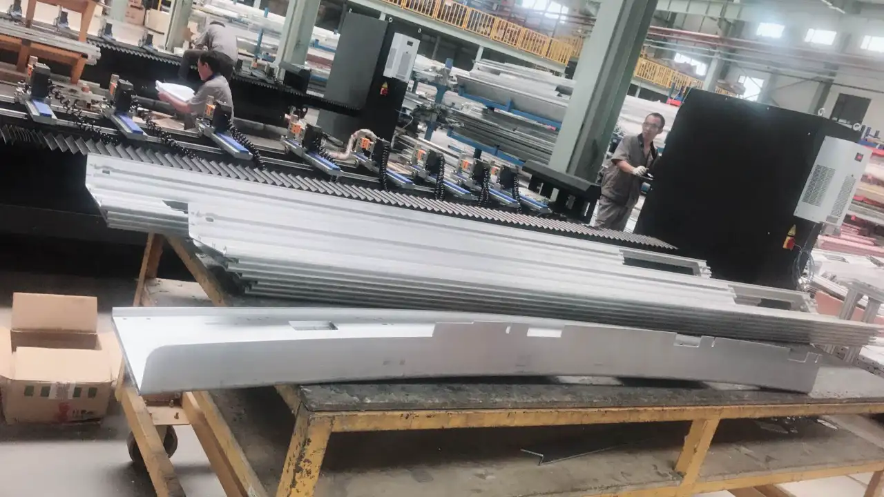 In a CNC machine manufacturer's factory, workers operate equipment amidst large, precision-machined aluminum aerospace components, demonstrating the use of CNC machines in producing aerospace parts.