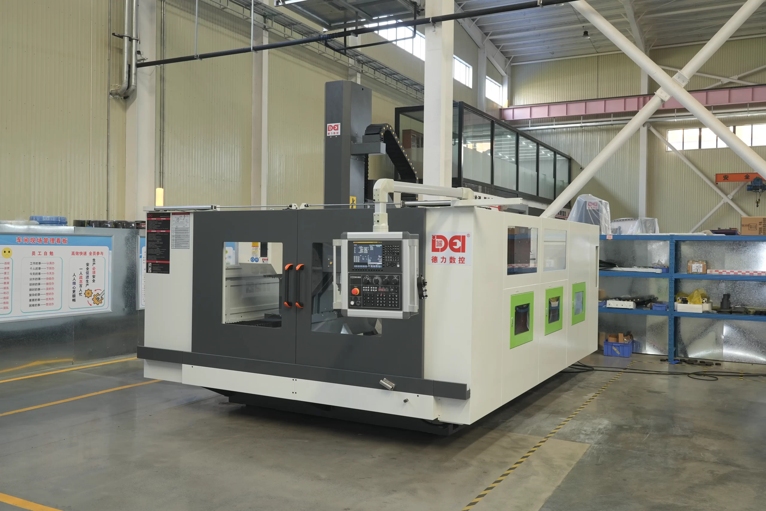 A DELI CNC gantry machining center (gantry structure) in a factory, featuring a control system, green side panels, and placed next to storage shelves with equipment.