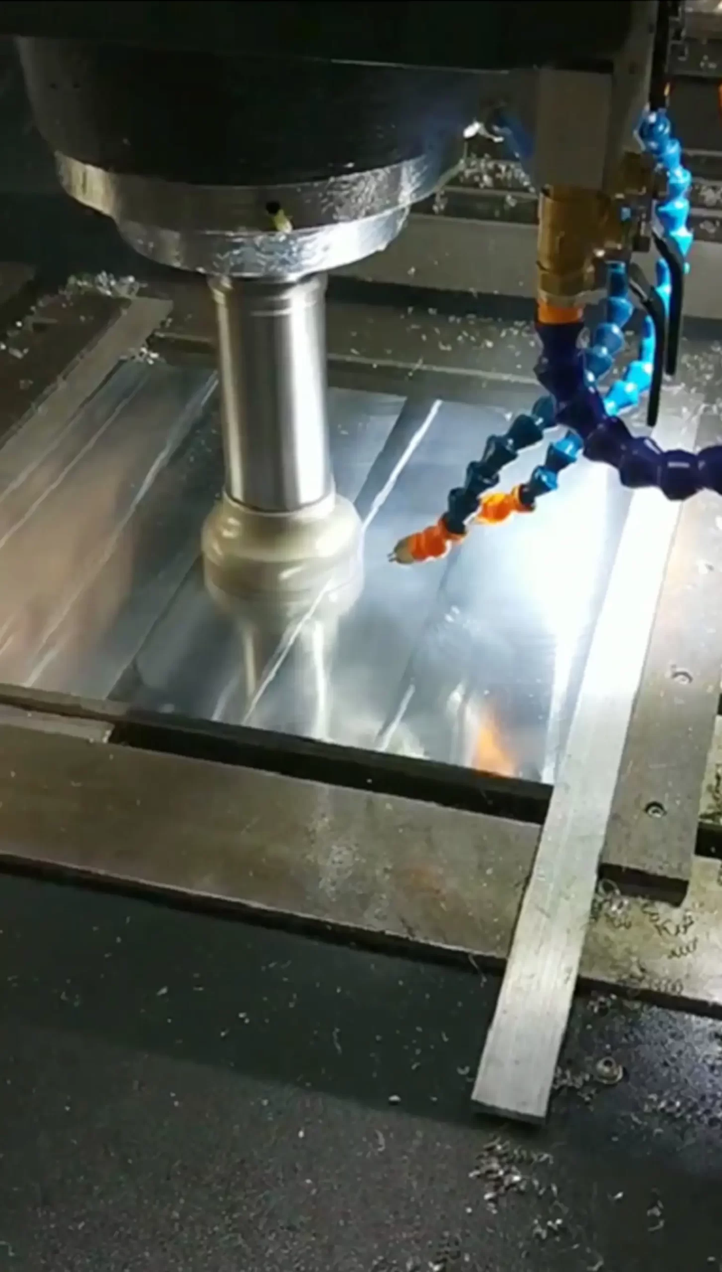 Close-up of a vertical machining center’s spindle milling an aluminum part. Coolant nozzles direct fluid to the cutting area, reducing heat and removing chips, while the machine performs high-precision milling for industrial components.